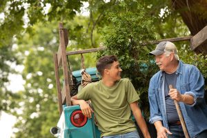 Grandson and grandpa smiling at each other while sitting on a truck bed.