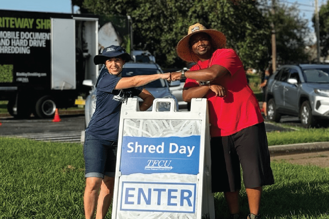 Two people fist bumping above a signage that says shred day.