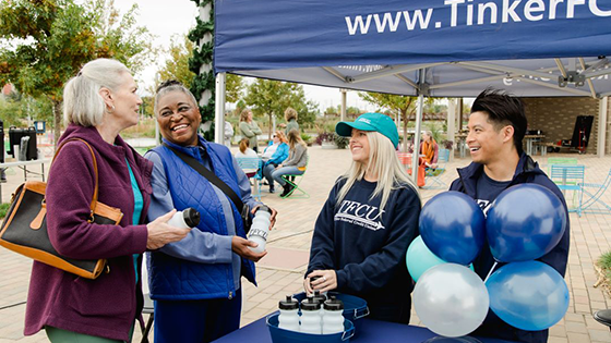 Two TFCU employees talking to two older women at a community event.