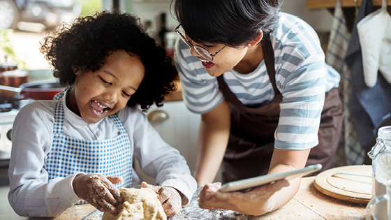 A mom helping a little girl with baking