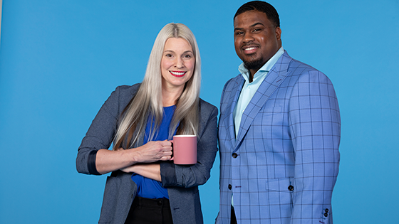 Two employees, a woman and a man, standing next to each.