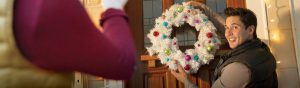 Man hanging a holiday wreath on a door