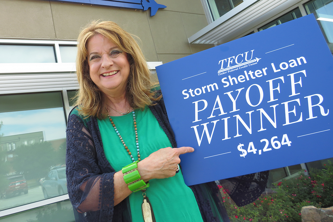 A TFCU member holding up a sign that says storm shelter payoff winner
