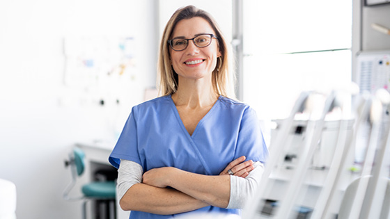 A nurse smiling at the camera with their arms folded.