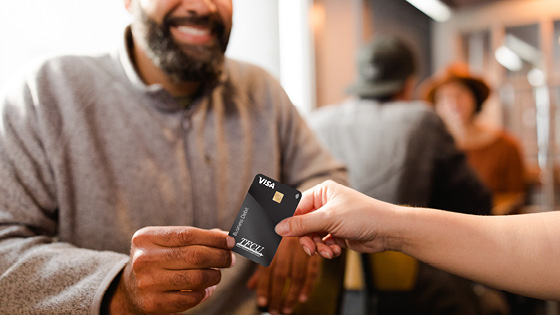 Close up of a man holding a black moneyplus debit card