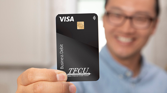 Close up of a man holding up a black business debit card