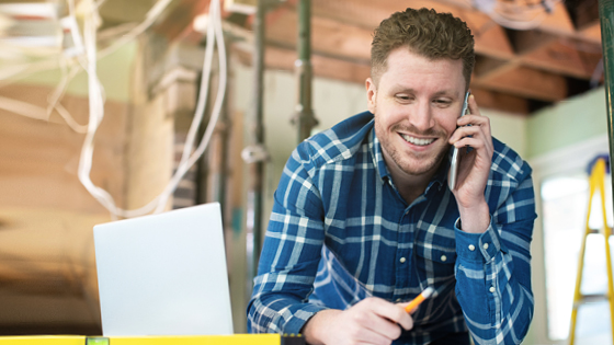 A man talking on the phone while in a house that's under construction