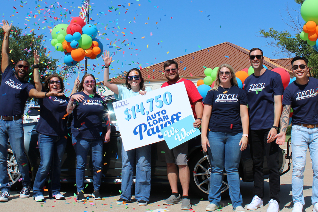 Group of TFCU employees standing with two members with balloons and confetti in the air