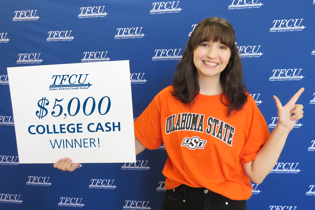 A student holding up a sign that says $5,000 college cash winner