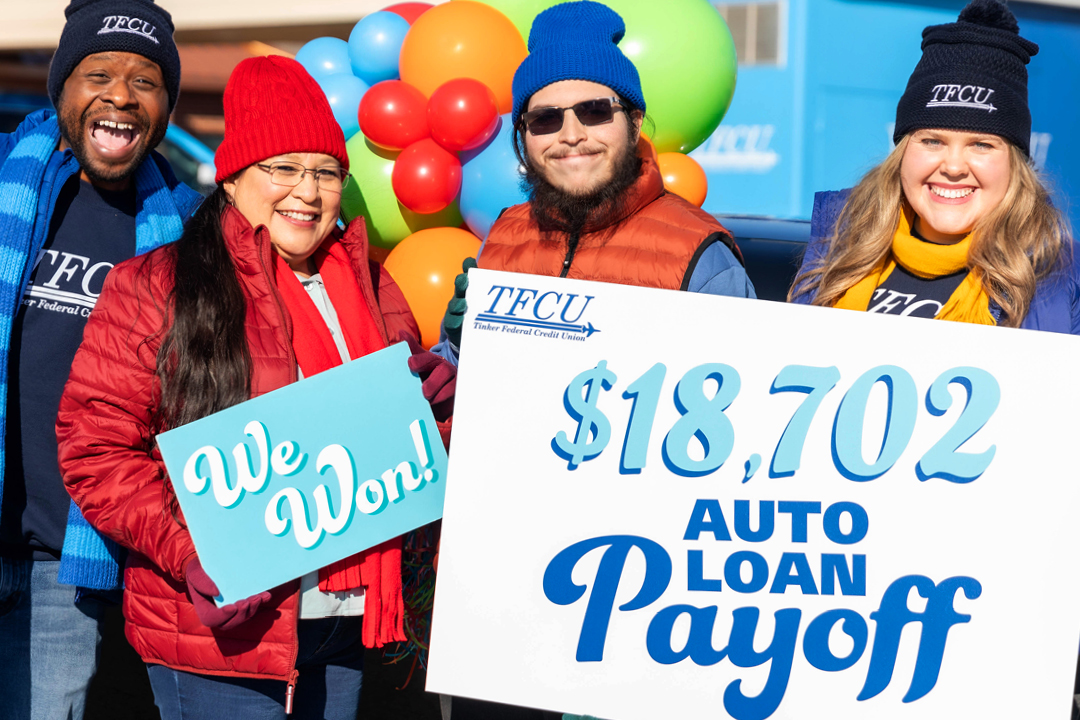 A mom and son with TFCU employees standing in front of balloons holding a sign that says auto loan payoff.