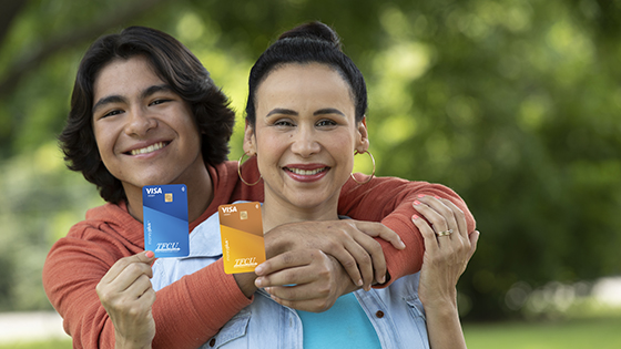 Son hugging is mom from behind while they are both holding up moneyplus cards