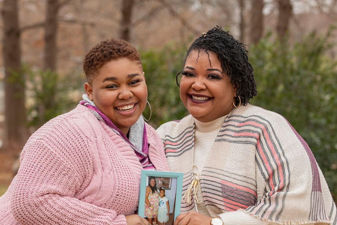 Mom and daughter looking at the camera while holding a picture frame