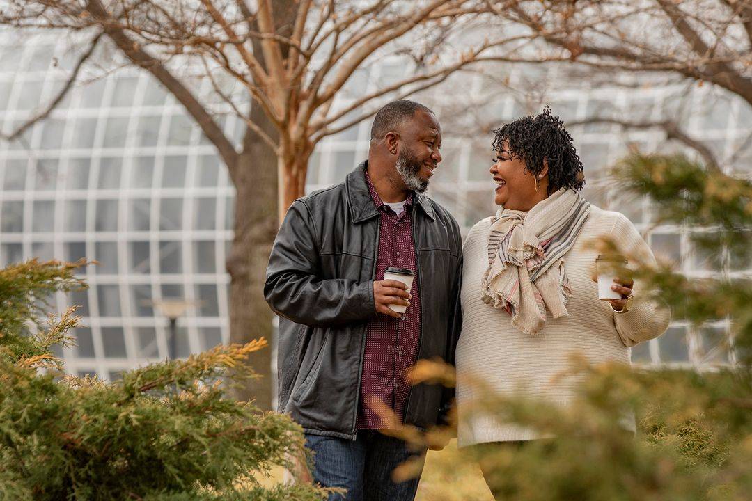 Two couple in a park with coffee in their hands and looking at each other