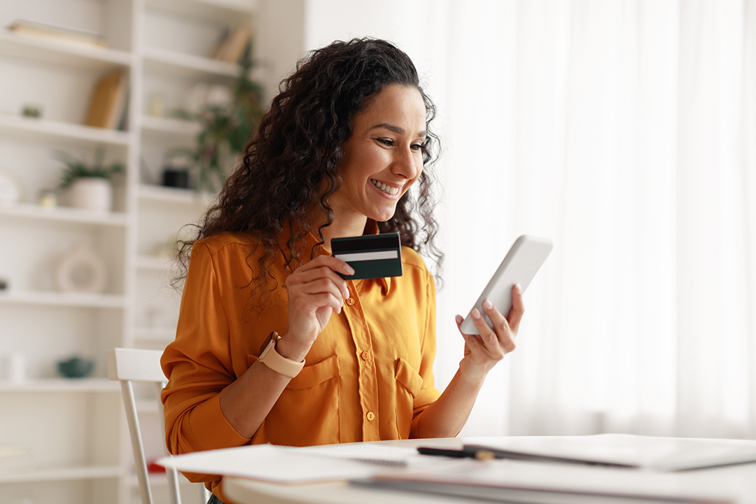 A woman holding a credit card and mobile device