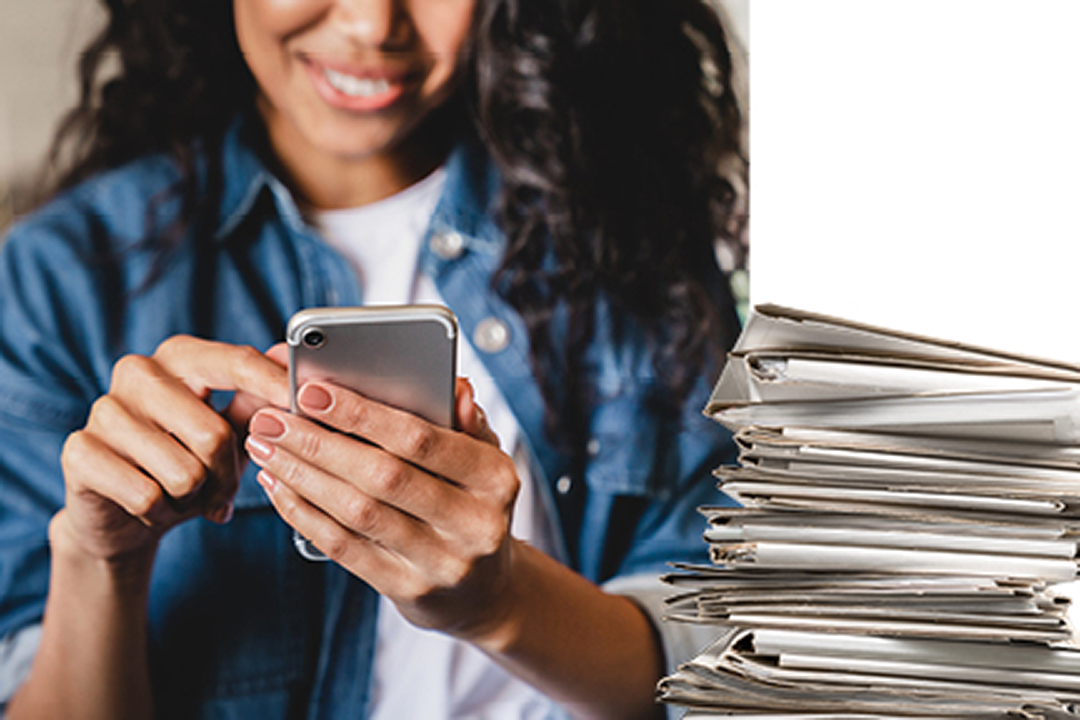 A close up of a woman on her mobile phone with a stack of papers on the right side