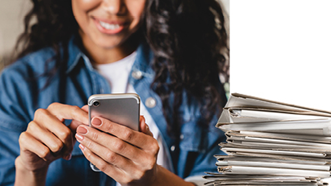 A close up of a woman on her mobile phone with a stack of papers on the right side