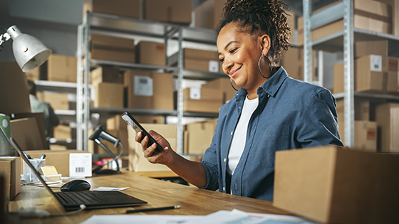 A woman in a warehouse holding a mobile device